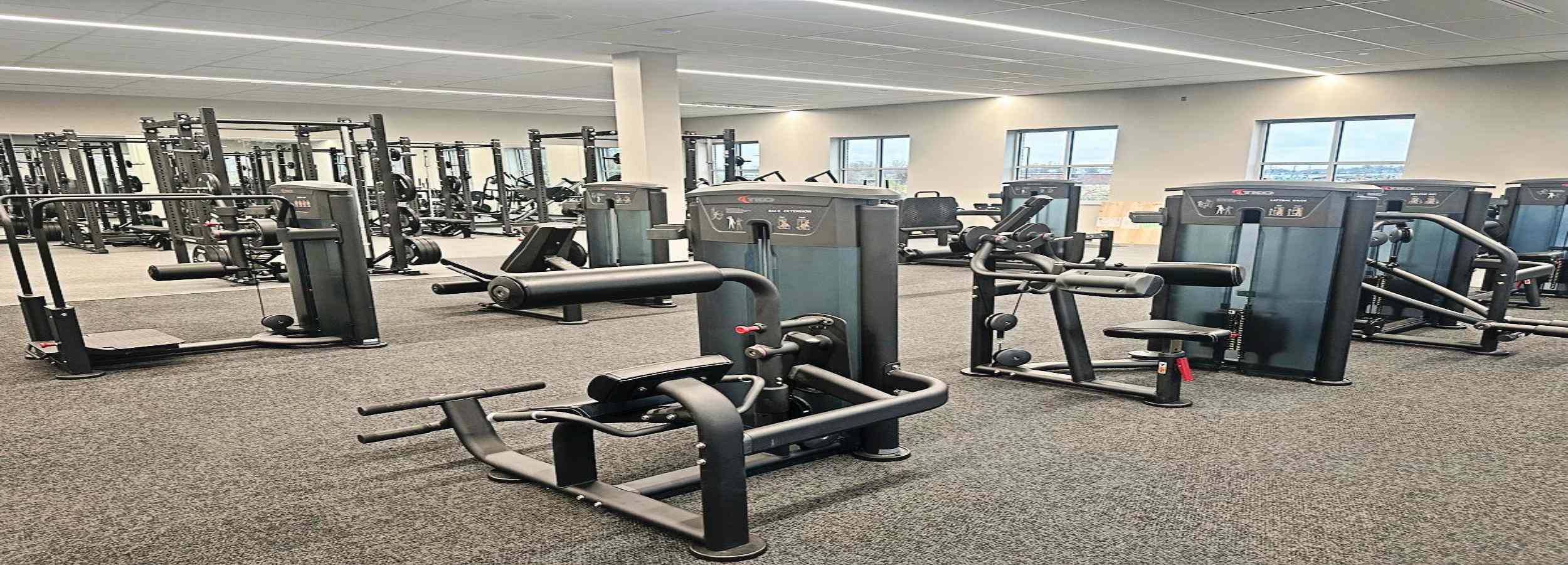 Gym interior with various exercise machines and equipment.