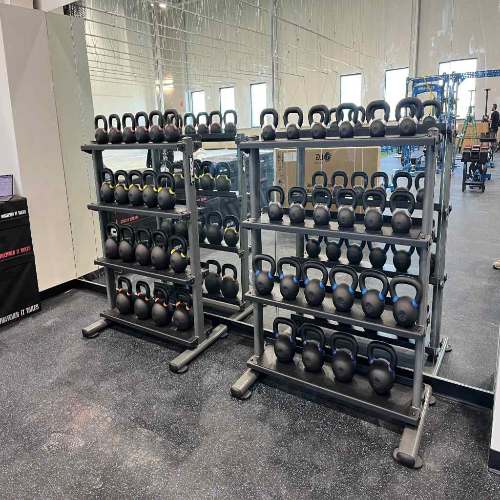 Two metal racks filled with kettlebells in a gym setting.